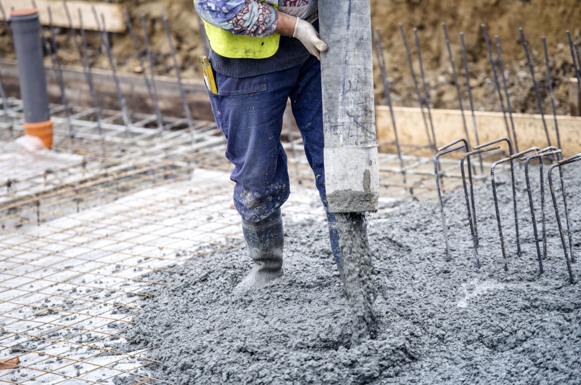 Concrete contractor pouring and leveling a concrete slab with rebar reinforcement