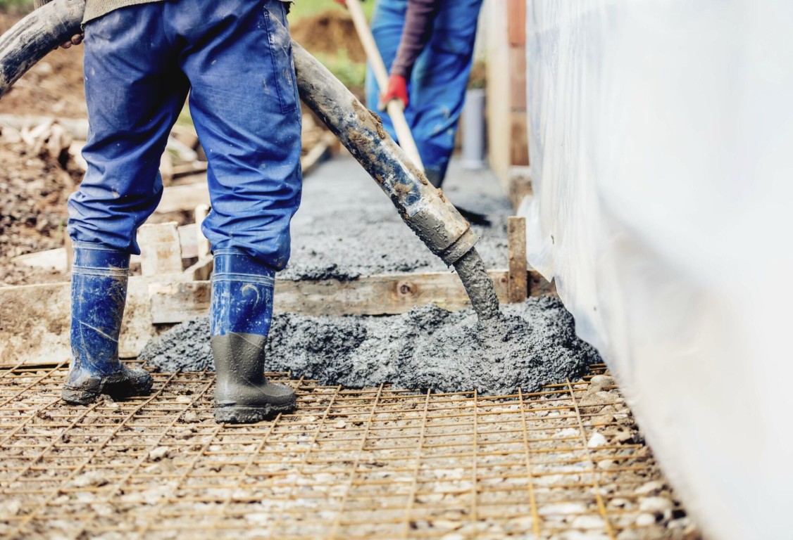 Concrete slab being poured over rebar reinforcement for a foundation