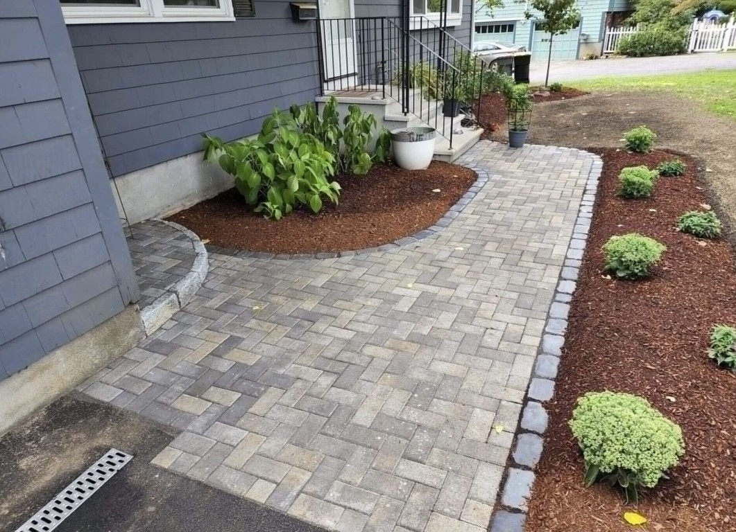 Concrete and paver walkway leading to a residential entryway